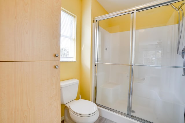 bathroom featuring toilet, plenty of natural light, and an enclosed shower