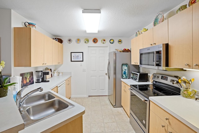 kitchen featuring sink, light brown cabinetry, appliances with stainless steel finishes, and a textured ceiling