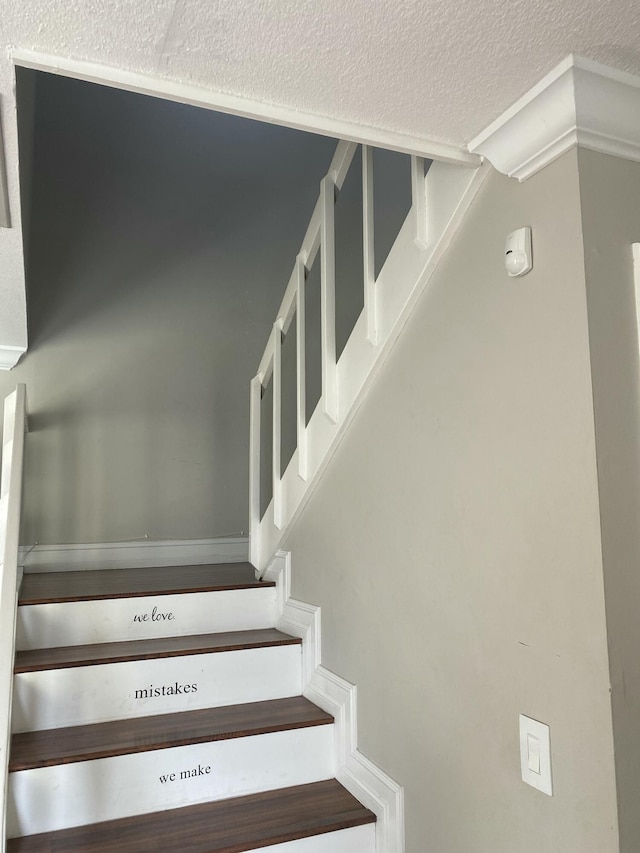 stairway featuring a textured ceiling