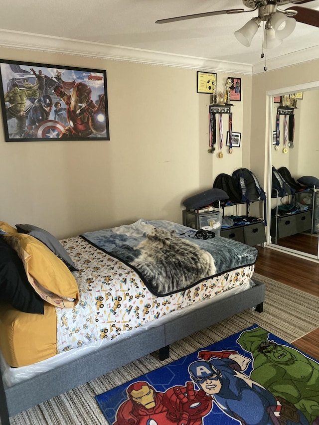 bedroom with hardwood / wood-style flooring, ceiling fan, ornamental molding, and a closet