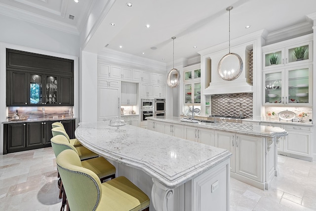 kitchen featuring hanging light fixtures, white cabinetry, decorative backsplash, and a spacious island