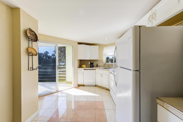 kitchen featuring sink, white cabinets, white appliances, decorative backsplash, and light tile patterned floors