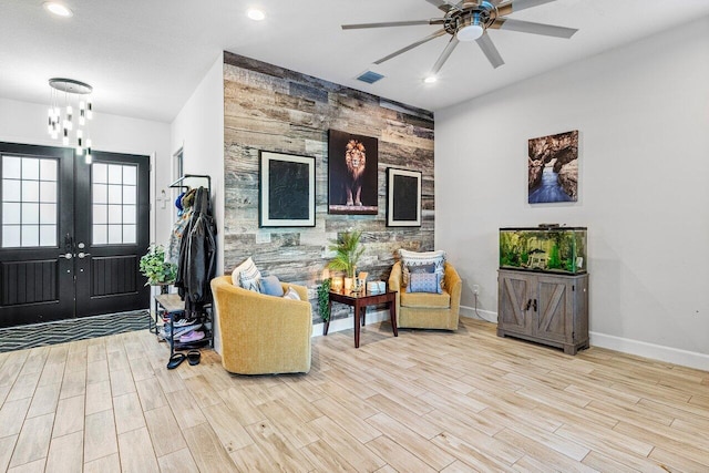 interior space featuring french doors, ceiling fan with notable chandelier, and light hardwood / wood-style flooring