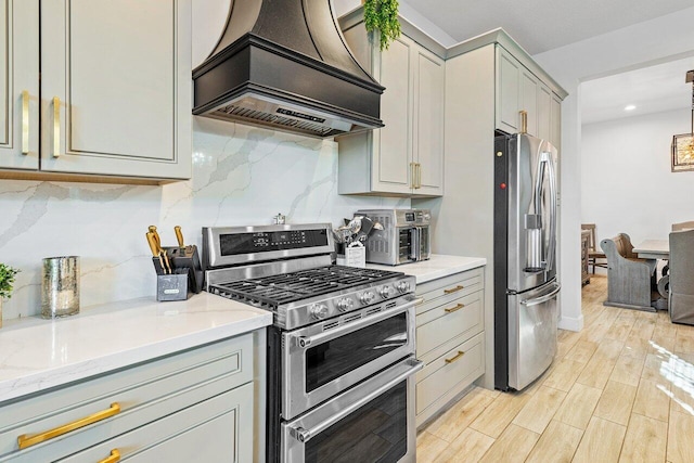 kitchen with gray cabinetry, light wood-type flooring, decorative backsplash, appliances with stainless steel finishes, and custom exhaust hood