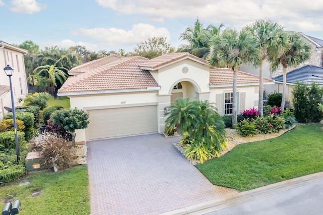 mediterranean / spanish-style house with a garage and a front lawn