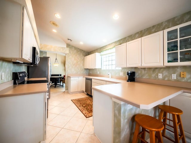 kitchen with hanging light fixtures, kitchen peninsula, lofted ceiling, a kitchen bar, and white cabinets