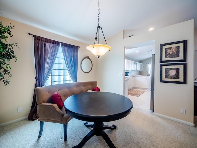 dining space featuring lofted ceiling and light carpet