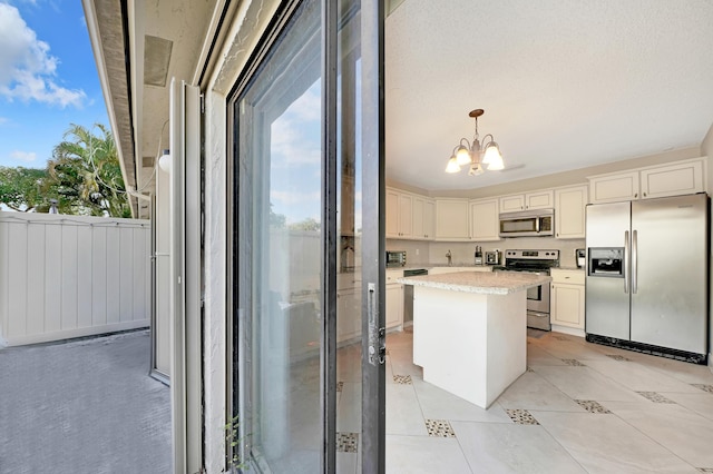 kitchen featuring appliances with stainless steel finishes, white cabinets, pendant lighting, a chandelier, and a kitchen island