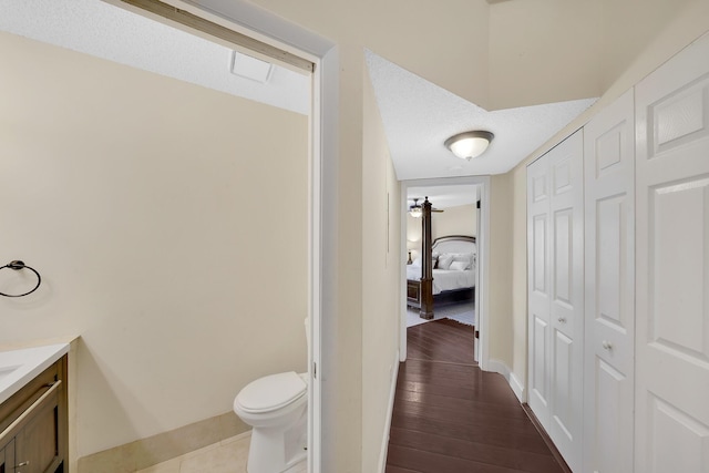 bathroom with hardwood / wood-style floors, vanity, a textured ceiling, and toilet