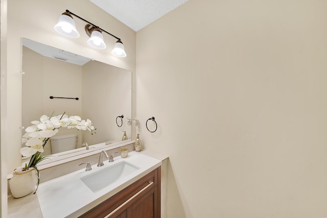 bathroom with vanity, a textured ceiling, and toilet