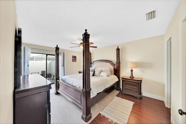 bedroom featuring access to outside, ceiling fan, dark wood-type flooring, and a textured ceiling