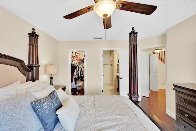 bedroom with hardwood / wood-style floors, ensuite bathroom, a walk in closet, ceiling fan, and a closet