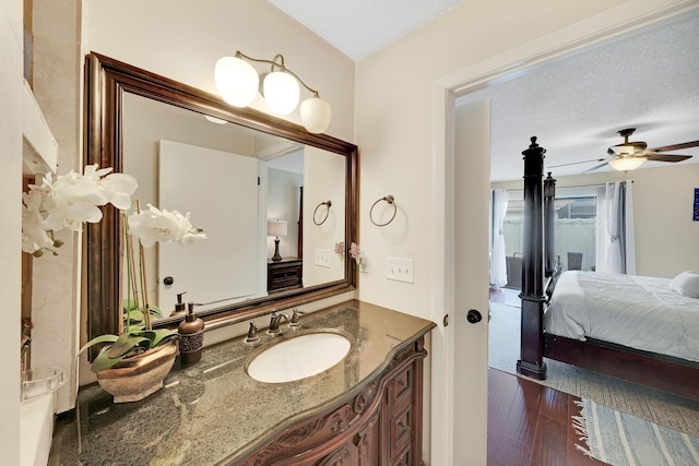 bathroom with ceiling fan, vanity, wood-type flooring, and a textured ceiling