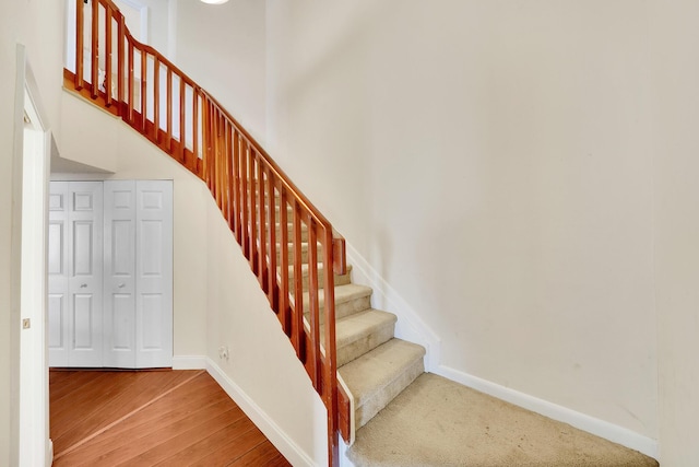 stairway featuring hardwood / wood-style floors and a towering ceiling