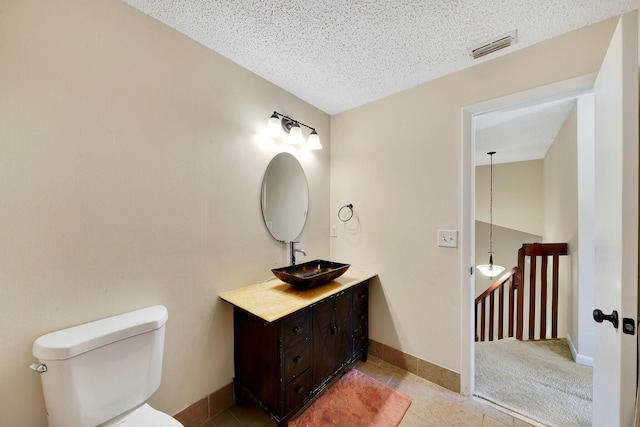 bathroom featuring tile patterned flooring, vanity, toilet, and a textured ceiling