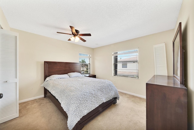 bedroom with a textured ceiling, ceiling fan, light carpet, and a closet