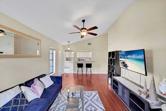 living room featuring a textured ceiling, dark hardwood / wood-style floors, ceiling fan, and lofted ceiling