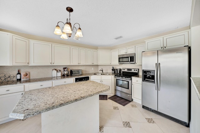 kitchen featuring sink, backsplash, decorative light fixtures, a kitchen island, and appliances with stainless steel finishes