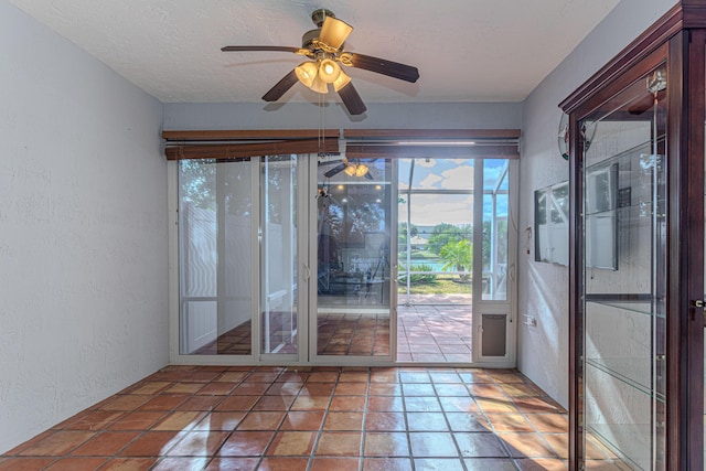 doorway with ceiling fan and a textured ceiling