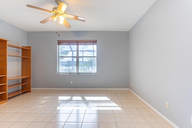 tiled empty room featuring ceiling fan and a textured ceiling