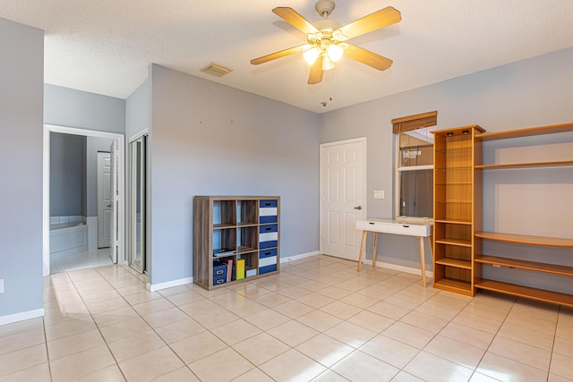 interior space with light tile patterned floors, a textured ceiling, and ceiling fan