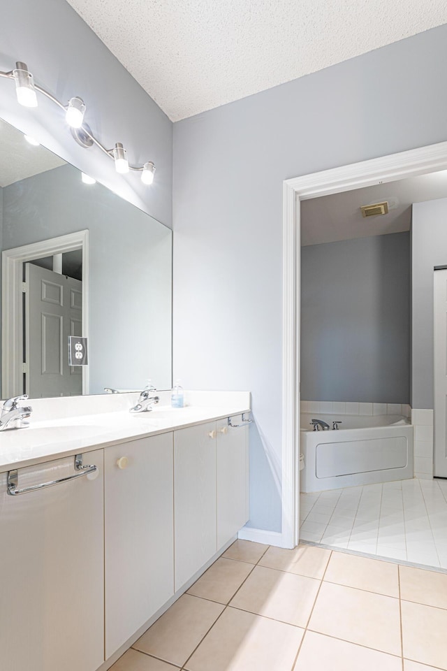 bathroom featuring tile patterned floors, vanity, a bath, and a textured ceiling