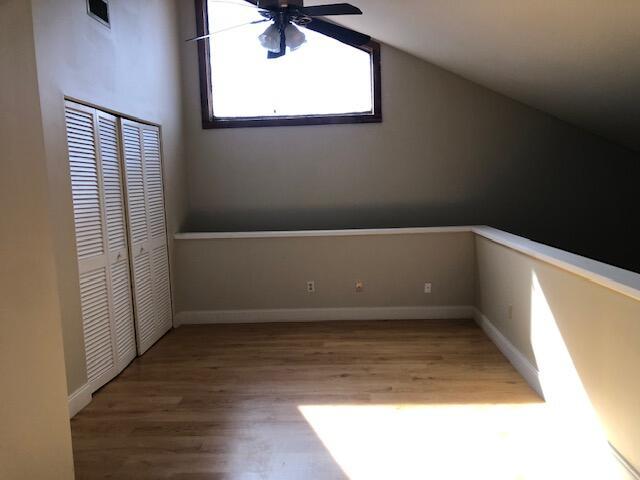 additional living space with hardwood / wood-style floors, vaulted ceiling, and ceiling fan