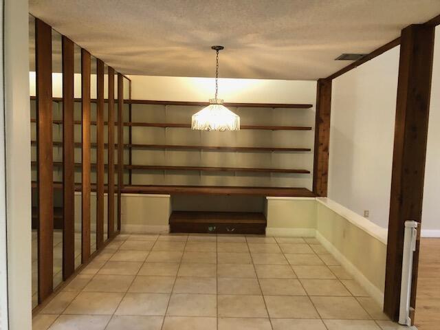 unfurnished dining area with light tile patterned flooring and a textured ceiling