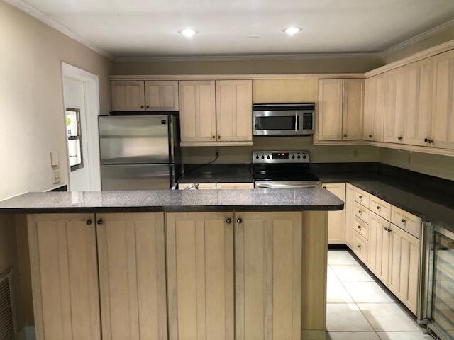 kitchen featuring light brown cabinets, beverage cooler, appliances with stainless steel finishes, light tile patterned floors, and ornamental molding