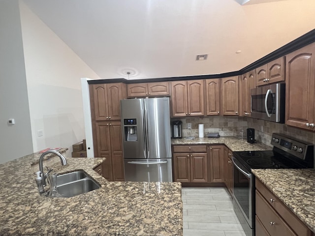 kitchen featuring sink, stainless steel appliances, light hardwood / wood-style flooring, dark stone counters, and decorative backsplash