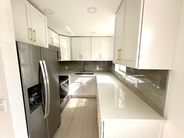 kitchen featuring white cabinetry, sink, tasteful backsplash, light hardwood / wood-style flooring, and appliances with stainless steel finishes