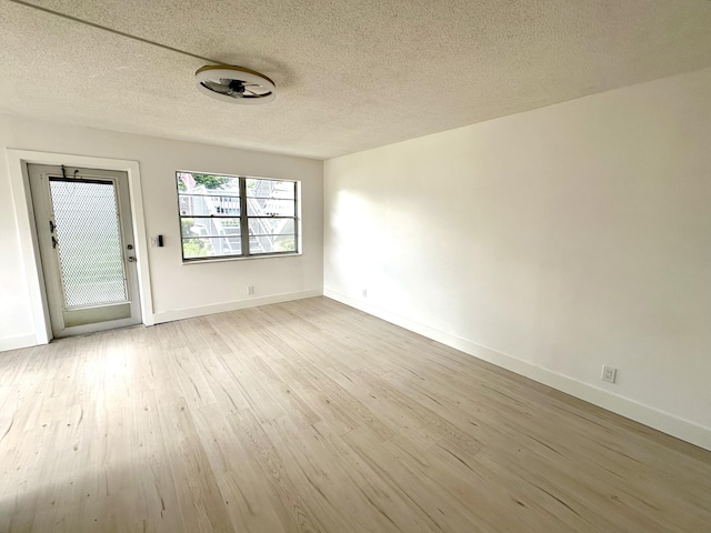 unfurnished room featuring a textured ceiling and light wood-type flooring