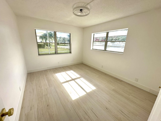 unfurnished room featuring light hardwood / wood-style floors and a textured ceiling