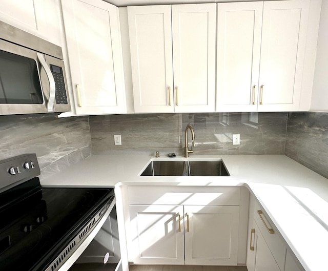 kitchen with white cabinets, black range with electric stovetop, sink, and tasteful backsplash