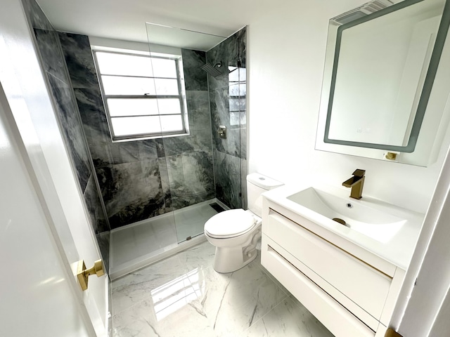 bathroom with tiled shower, vanity, and toilet