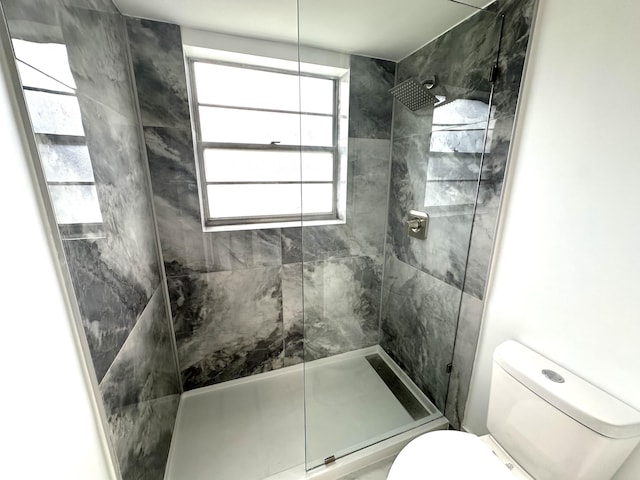 bathroom featuring tiled shower and toilet