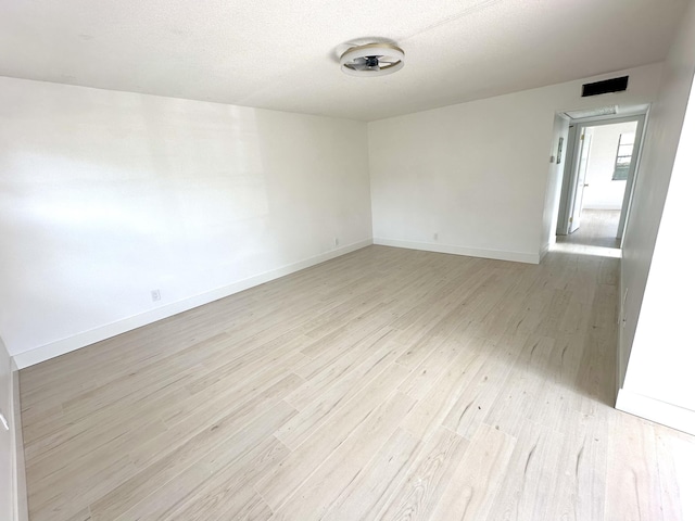 empty room with a textured ceiling and light hardwood / wood-style flooring