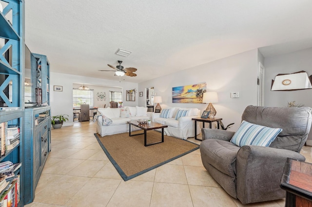 living room with ceiling fan, light tile patterned floors, and a textured ceiling