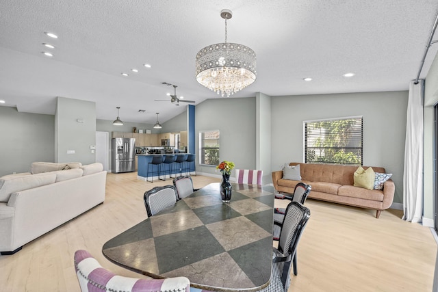 dining room with ceiling fan with notable chandelier, light hardwood / wood-style floors, lofted ceiling, and a textured ceiling