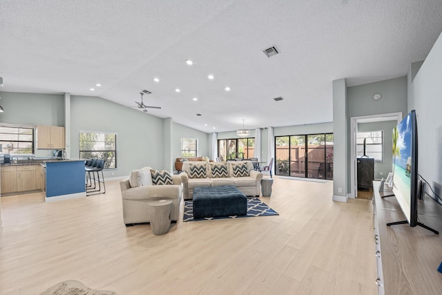 living room with light wood-type flooring, ceiling fan, and lofted ceiling