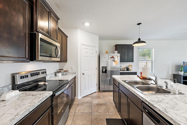 kitchen with appliances with stainless steel finishes, decorative light fixtures, dark brown cabinets, and sink