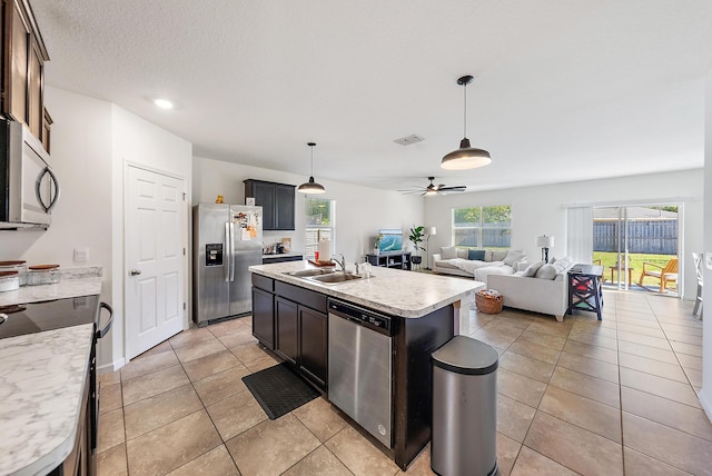 kitchen featuring ceiling fan, sink, hanging light fixtures, stainless steel appliances, and an island with sink