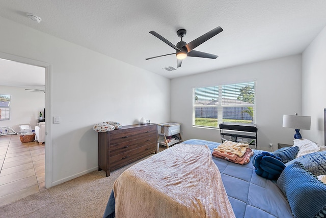 tiled bedroom with ceiling fan and a textured ceiling