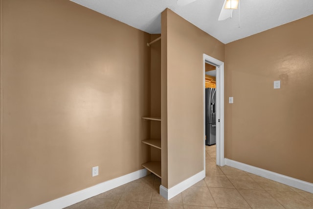 interior space featuring stainless steel fridge, light tile patterned floors, and ceiling fan