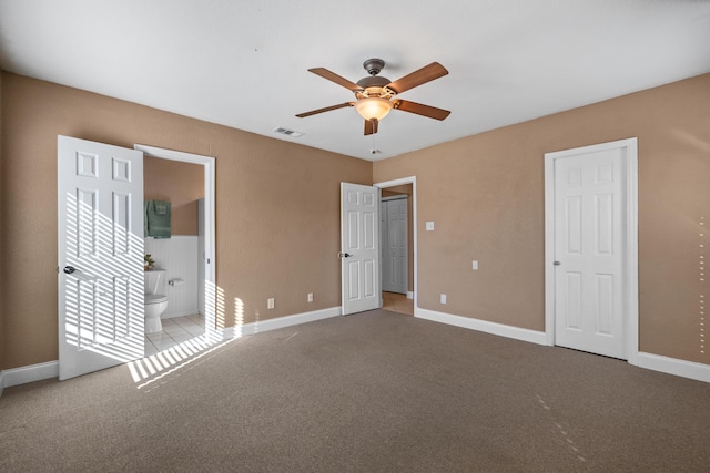 unfurnished bedroom featuring light carpet, connected bathroom, and ceiling fan