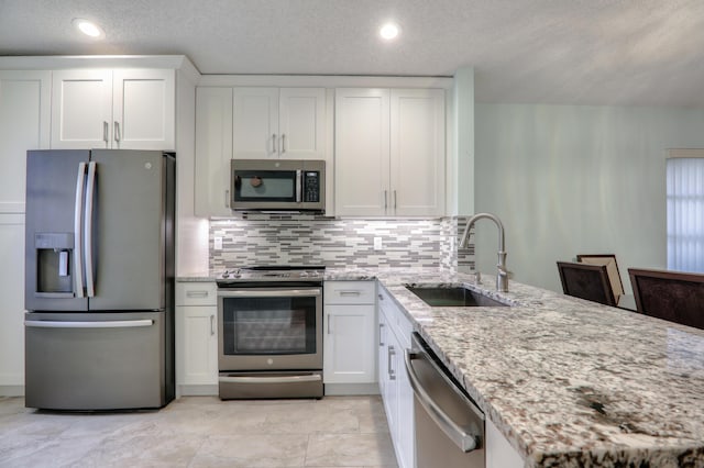 kitchen featuring light stone countertops, white cabinetry, sink, and stainless steel appliances