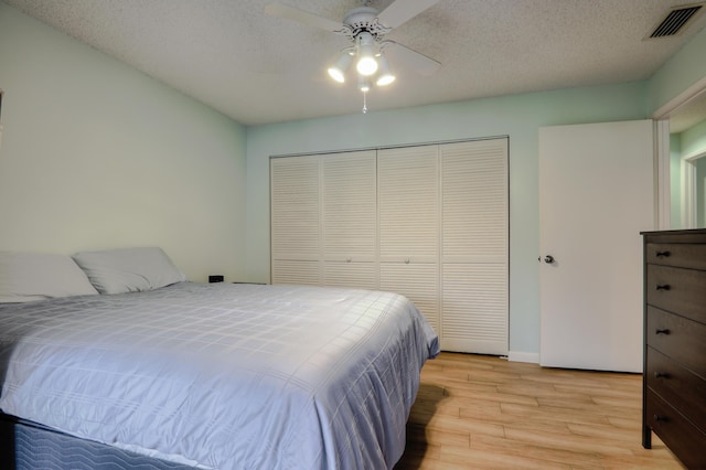 bedroom with ceiling fan, a closet, a textured ceiling, and light hardwood / wood-style flooring