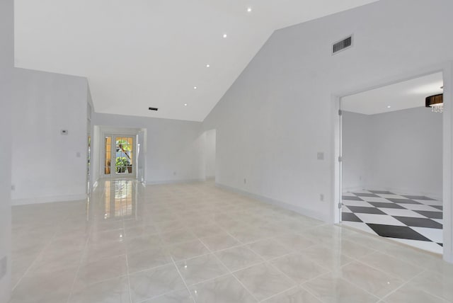 empty room featuring high vaulted ceiling and light tile patterned flooring