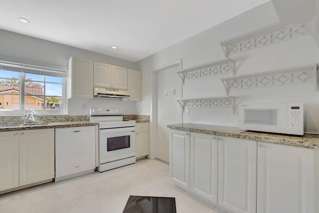 kitchen with white appliances, white cabinets, sink, light tile patterned floors, and light stone counters