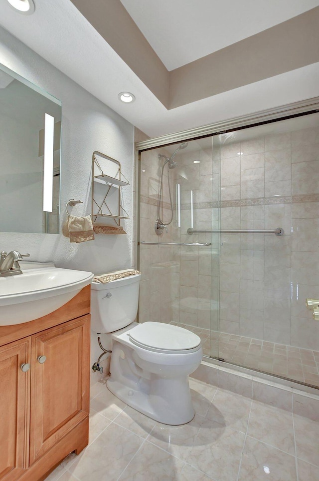 bathroom with tile patterned floors, vanity, toilet, and a shower with door